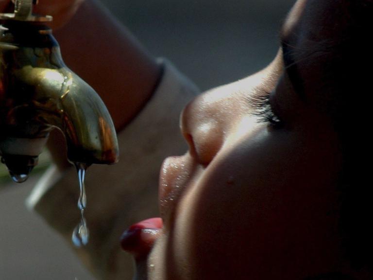 Ein jemenitisches Kind trinkt an einem Wasserhahn.