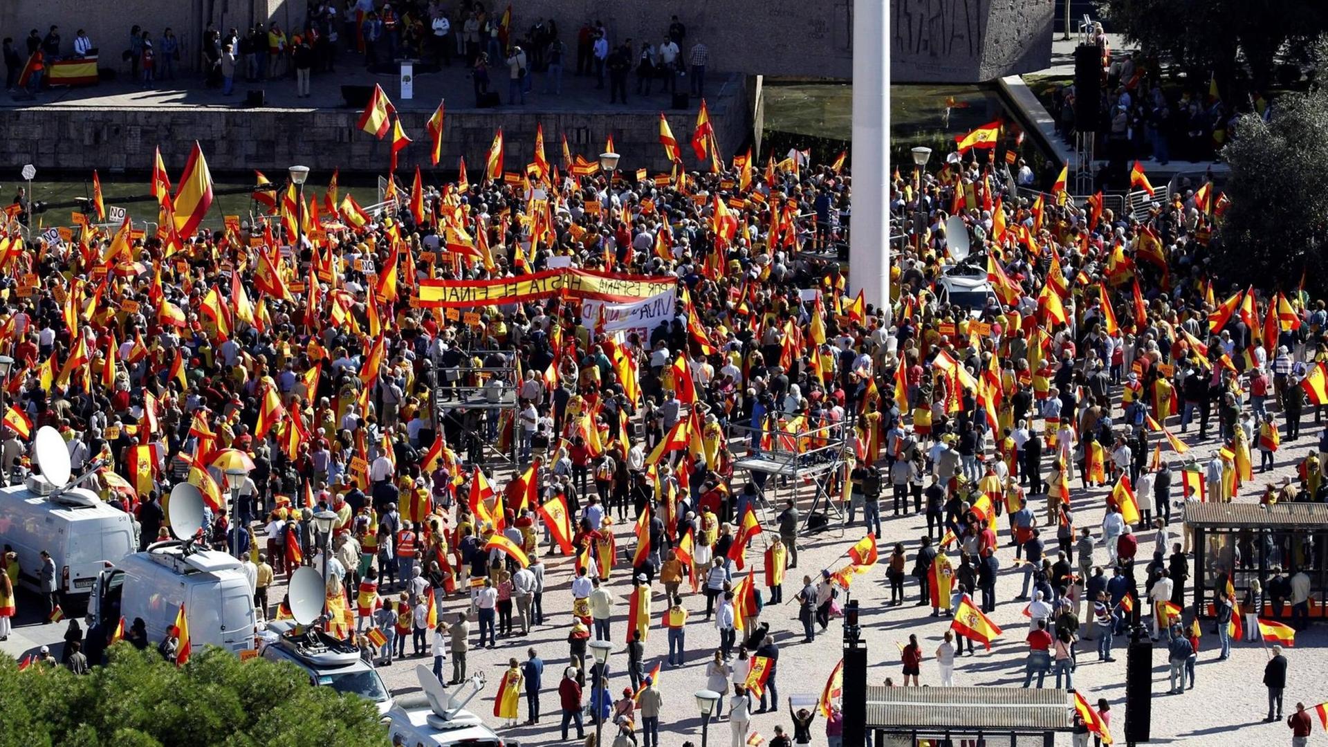 Sie sehen Demonstranten in Madrid mit der spanischen Flagge.
