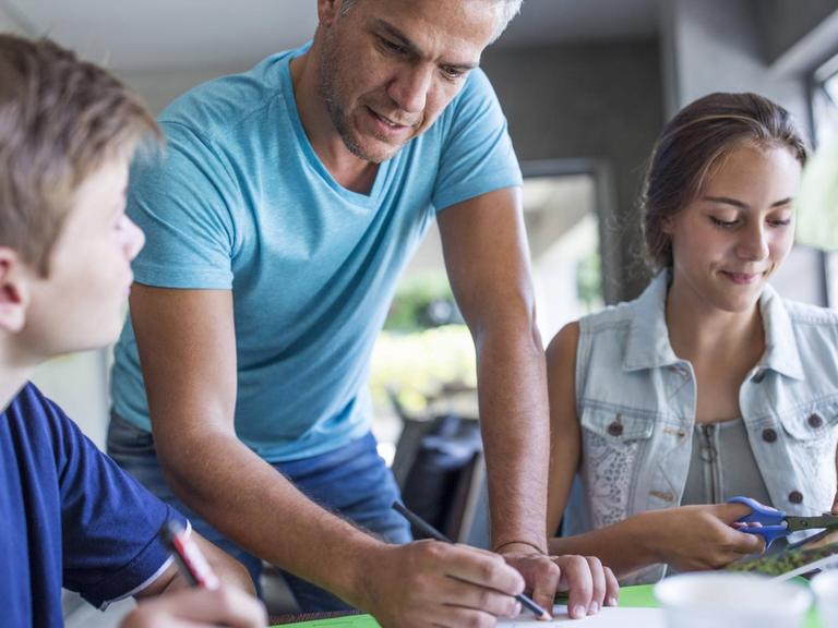 Ein Vater mit Tochter und Sohn bei den Hausaufgaben