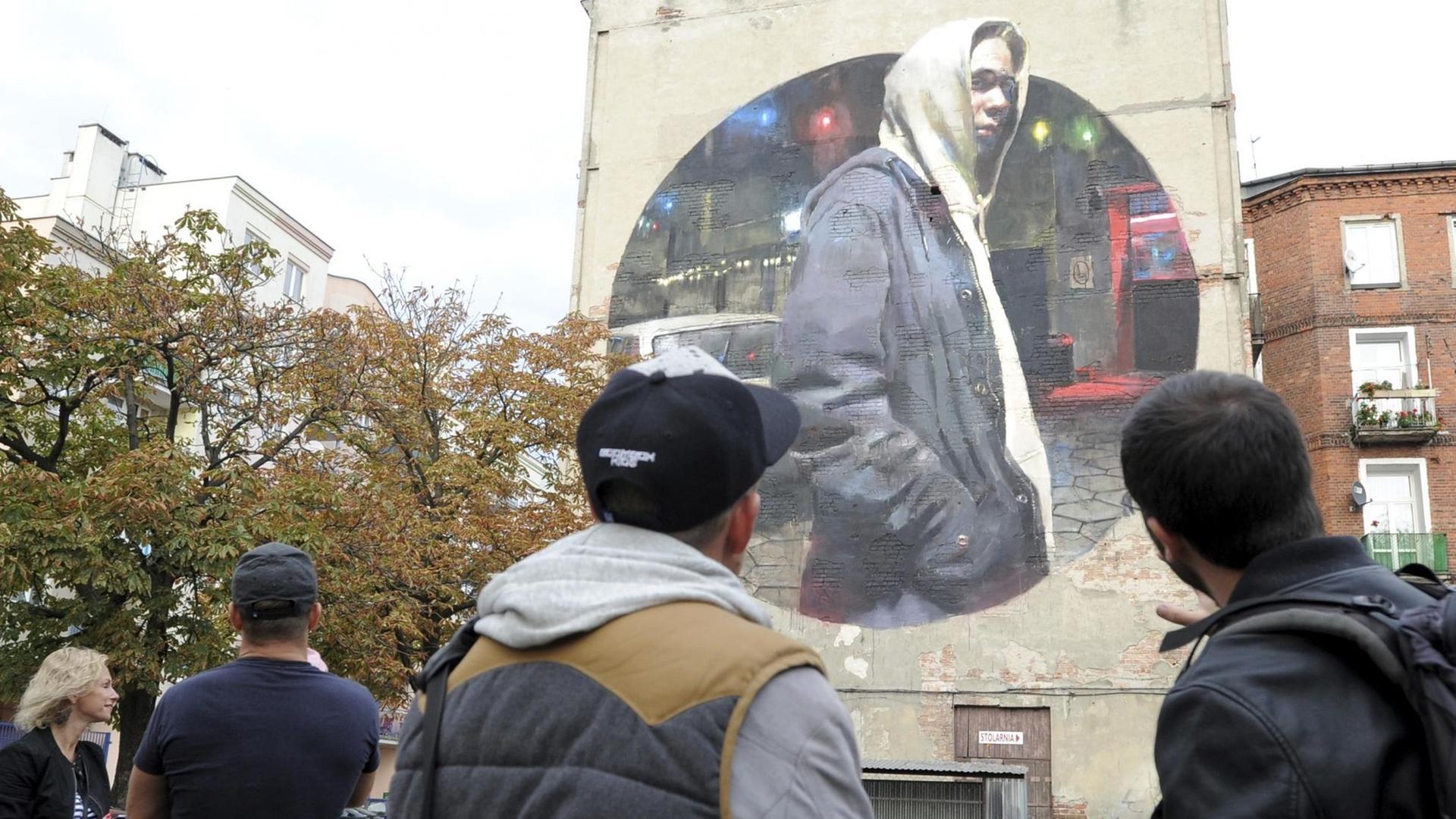 Jugendliche vor einem Wandgemälde des spanischen Street Art-Künstlers Sebas Velasco im Stadtteil Praga in Warschau.