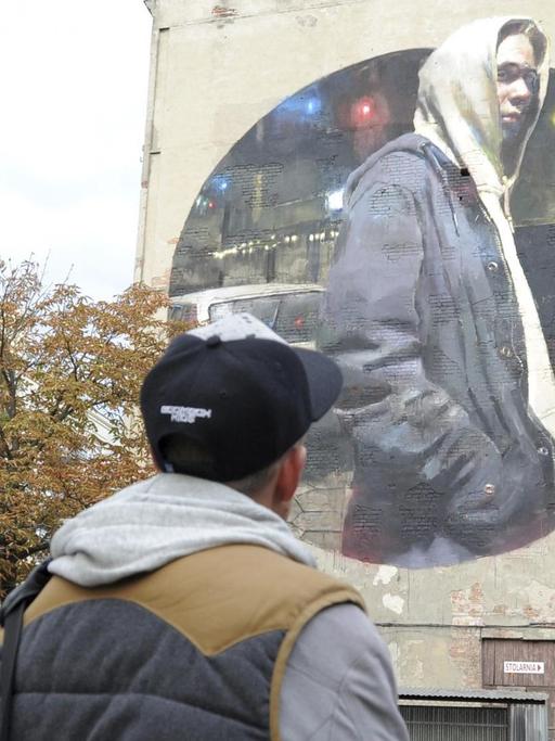 Jugendliche vor einem Wandgemälde des spanischen Street Art-Künstlers Sebas Velasco im Stadtteil Praga in Warschau.