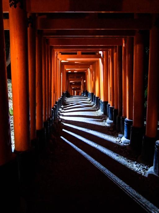 Ein traditioneller Säulengang mit rotlackierten Stelen am Fushimi Inari Taisha Schrein in Kyoto, der ehemaligen Kaiserstadt.