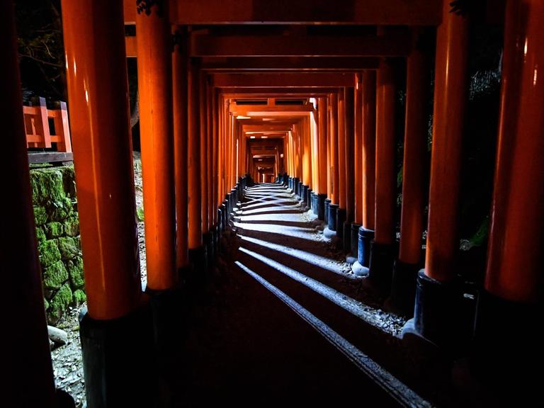 Ein traditioneller Säulengang mit rotlackierten Stelen am Fushimi Inari Taisha Schrein in Kyoto, der ehemaligen Kaiserstadt.