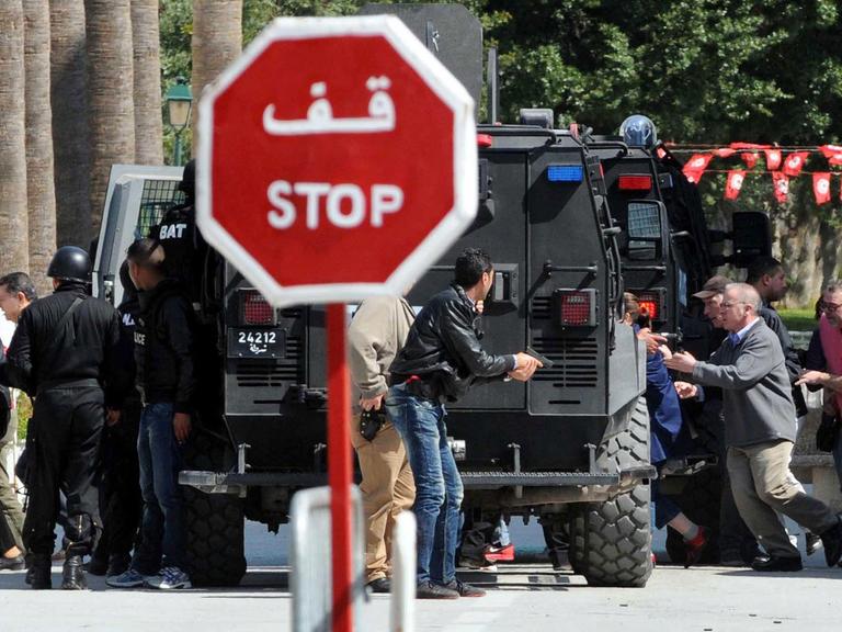 Sicherheitskräfte und andere Menschen laufen aus dem Nationalmuseum in Tunis.