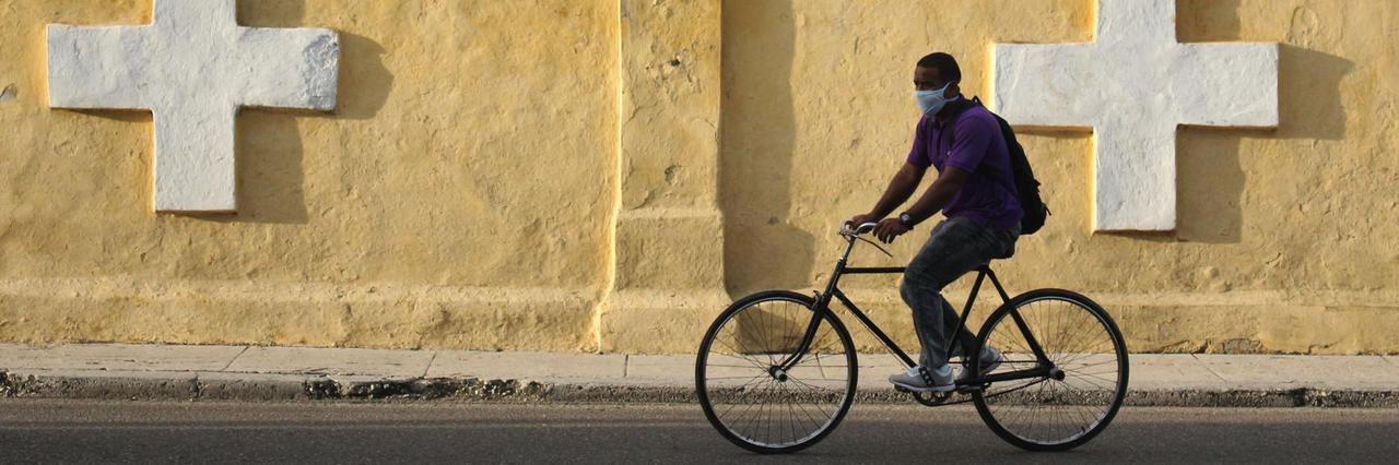 Ein Mann fährt mit dem Fahrrad an der Mauer des Colon-Friedhofes von Havanna entlang. 