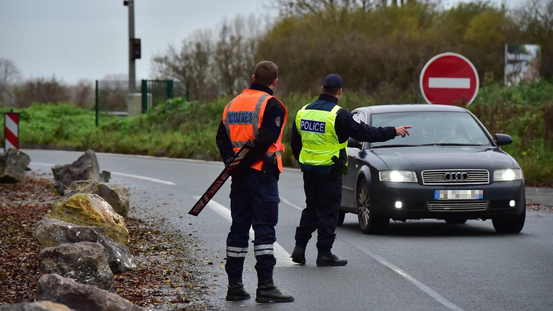 Ein uto wird an der französisch-belgischen Grenze von zwei Beamten gestoppt.