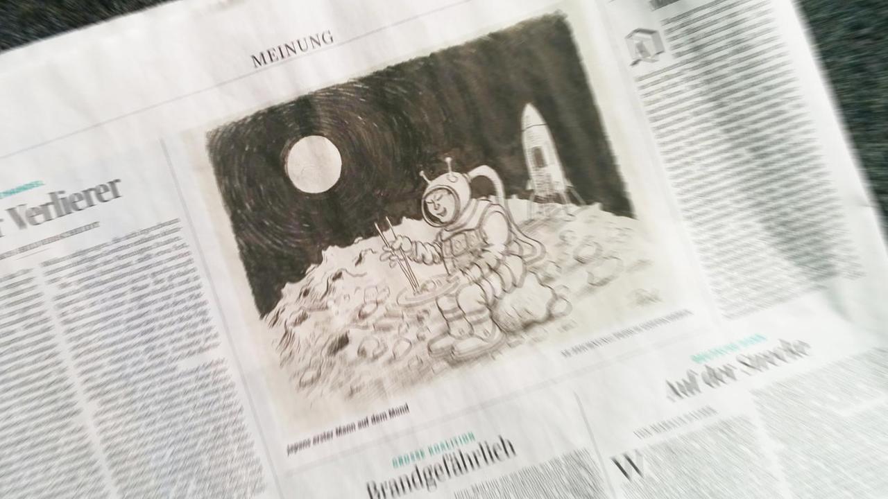 Eine Zeitungsseite der SZ mit einer Karikatur, die einen Astronauten mit Schlitzaugen zeigt, der auf dem Mond mit Stäbchen Sushi isst.
