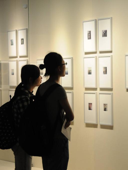 Besuchenden schauen sich Bilder der Berliner Fotografin Sibylle Bergemann in einer Ausstellung in Nanjing in China an.
