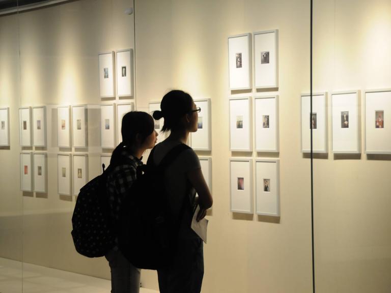 Besuchenden schauen sich Bilder der Berliner Fotografin Sibylle Bergemann in einer Ausstellung in Nanjing in China an.