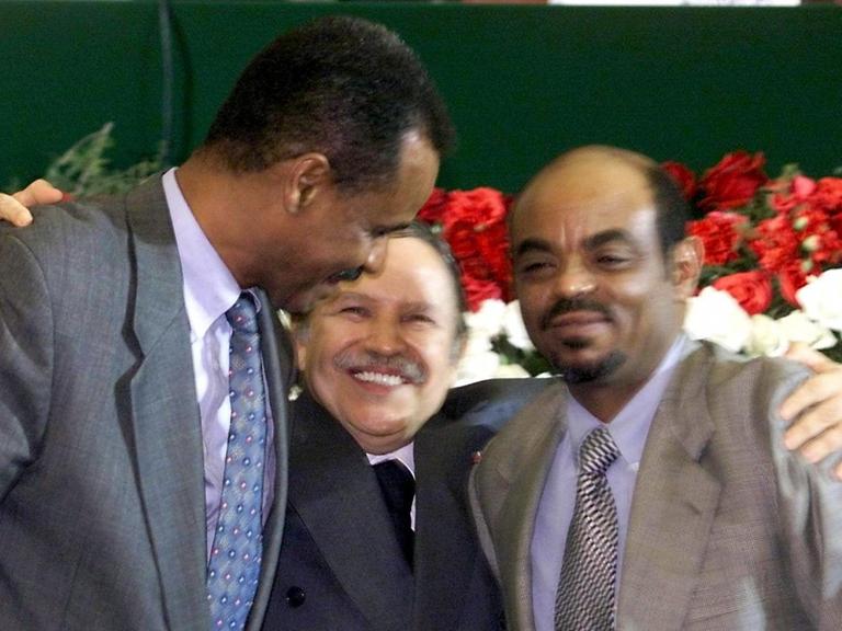 Ein Farbfoto zeigt den algerischen Präsidenten Abdelaziz Bouteflika mit dem Präsidenten Eritreas, Issaias Afewerki links von ihm und Äthiopiens Regierungschef Meles Zenawi rechts im Arm.