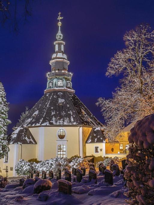Festlich beleuchtet in der Blauen Stunde ist die Bergkirche im verschneiten weihnachtlichen Seiffen. Viele Touristen besuchen in der Weihnachtszeit den Ort im Erzgebirge mit seinen vielen Herstellern von traditioneller Erzgebirgsicher Volkskunst.