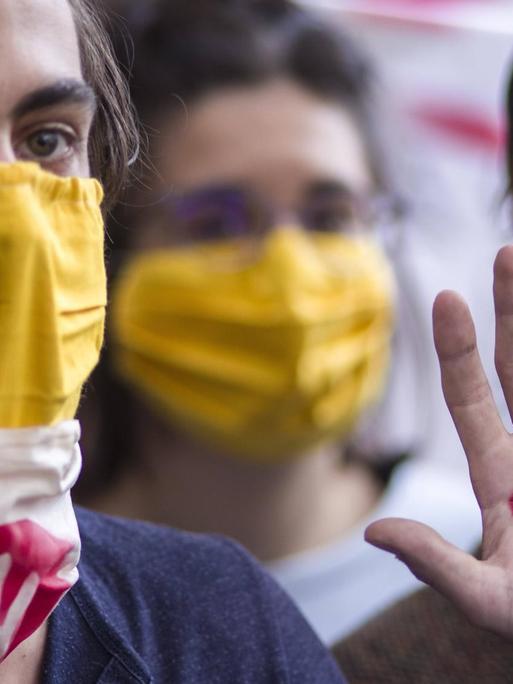 StudentInnen mit Corona-Mundschutz vor dem verbarrikadierten Haupteingang.