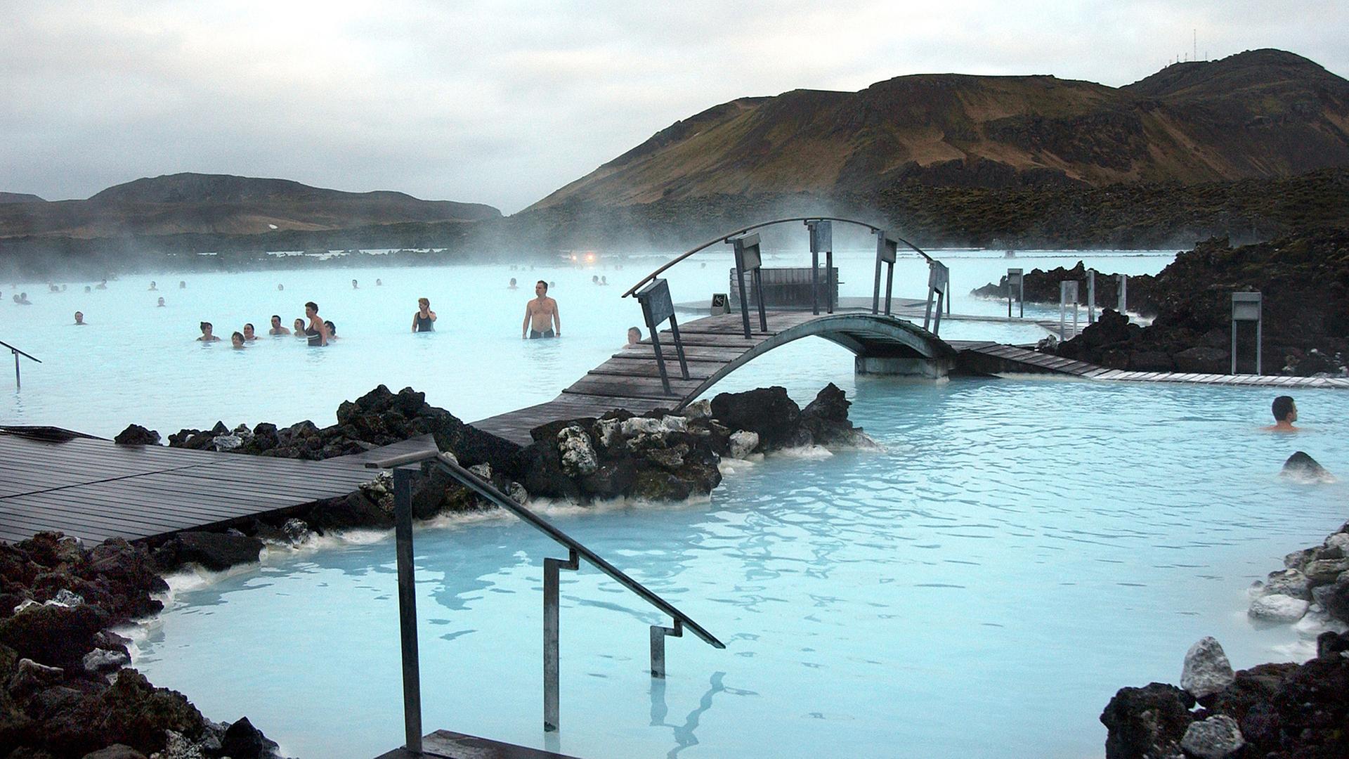 Badende vergnügen sich in dem türkisfarbenen Wasser der Blauen Lagune bei Reykjavík, Island.