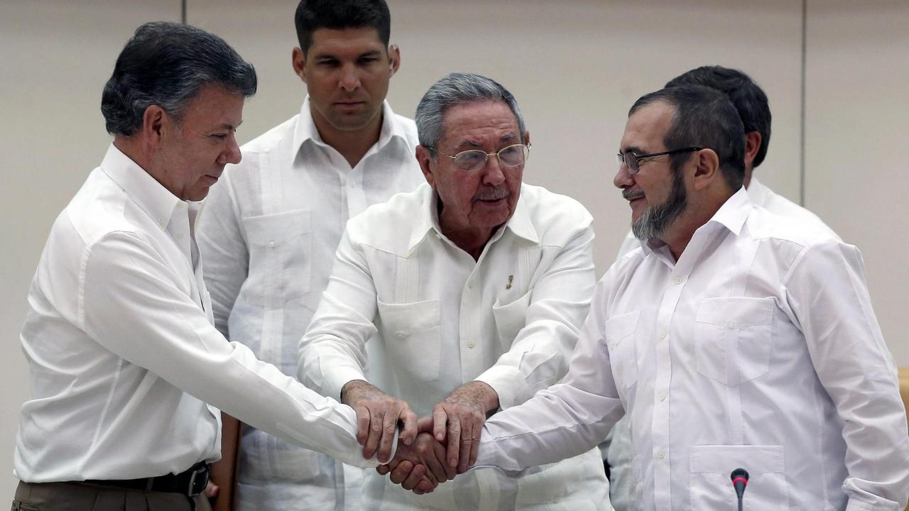 Der kubanische Präsident Raul Castro (M.) hält die Hände des kolumbianischen Präsidenten Juan Manuel Santos (l.) und des FARC-Führers Rodrigo Londono 'Timochenko' Echeverri (r.)