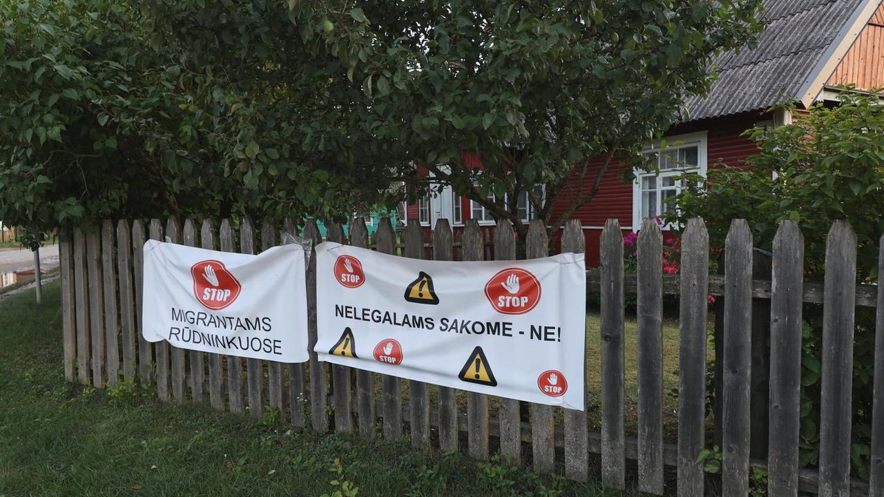 Ein Plakat gegen Flüchtlinge hängt an einem Gartenzaun in einer Ortschaft.