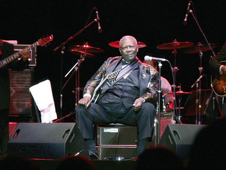 B. B. King sitzt auf einer Bühne.