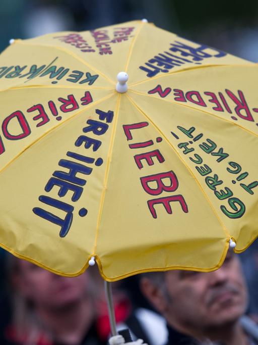 Ein Regenschirm mit der Aufschrift "Liebe, Freiheit, Gerechtigkeit", aufgenommen bei einer Demonstration
