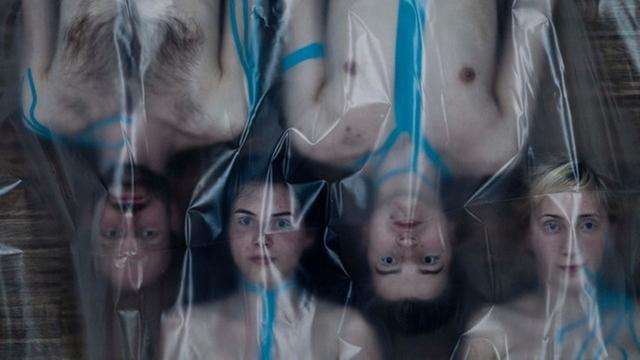 Eine Szene aus dem Stück "Cyborg-City" der Kompanie "Borgtheater – cyborg performing theater": Vier Schauspieler liegen mit nacktem Oberkörper auf dem Boden, bedeckt von einer Plastikfolie