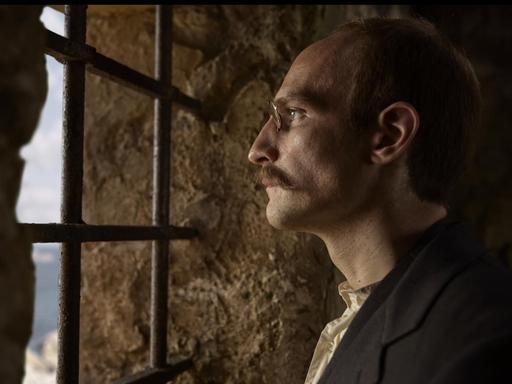 Eine Filmszene aus Polanskis Film Intrige zeigt den vermeintlichen Verräter Alfred Dreyfus (Louis Garrel) hinter Gittern.