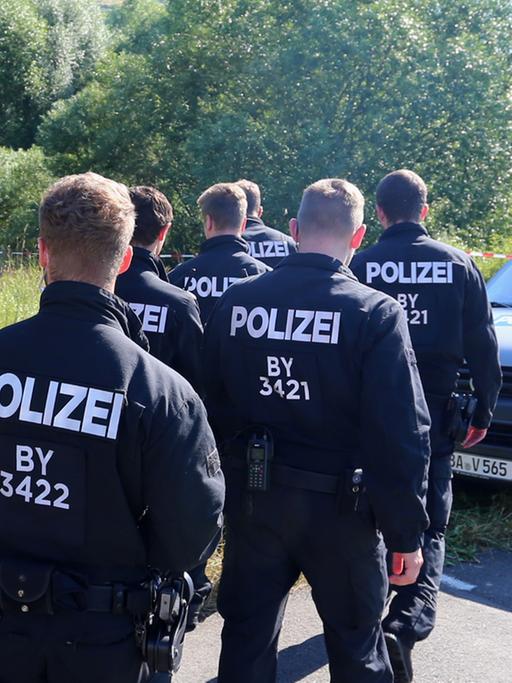 Polizisten durchsuchen am 19.07.2016 neben einem Weg bei Würzburg (Bayern) das Gelände nach Spuren. Am Montagabend war ein 17 Jahre alter Afghane mit einer Axt und einem Messer auf Fahrgäste in einem Regionalzug bei Würzburg-Heidingsfeld losgegangen.