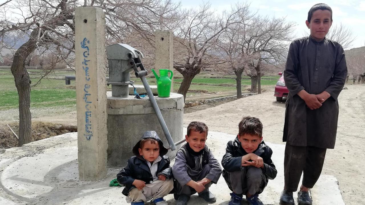 Vier Kinder im afghanischen Dorf Mussahi. Im Hintergrund ist ein Brunnen zu sehen.