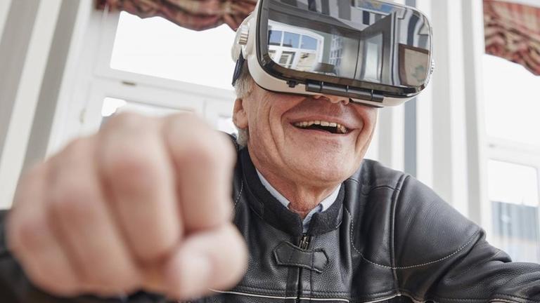 Ein älterer Mann mit Lederjacke trägt eine Virtual-Reality-Brille.