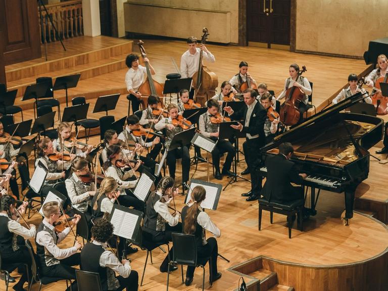 Das Jugendorchester spielt mit einem Pianisten in einem Konzertsaal in Kasan.