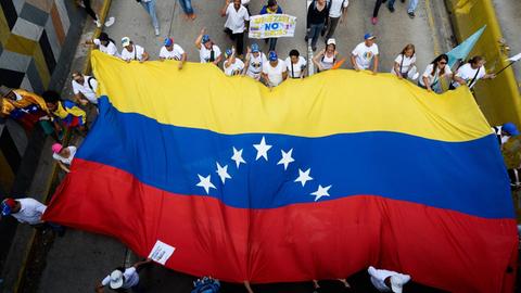 Teilnehmer einer Demonstration gegen Venezuelas Präsident Maduro mit einer venezolanischen Flagge.