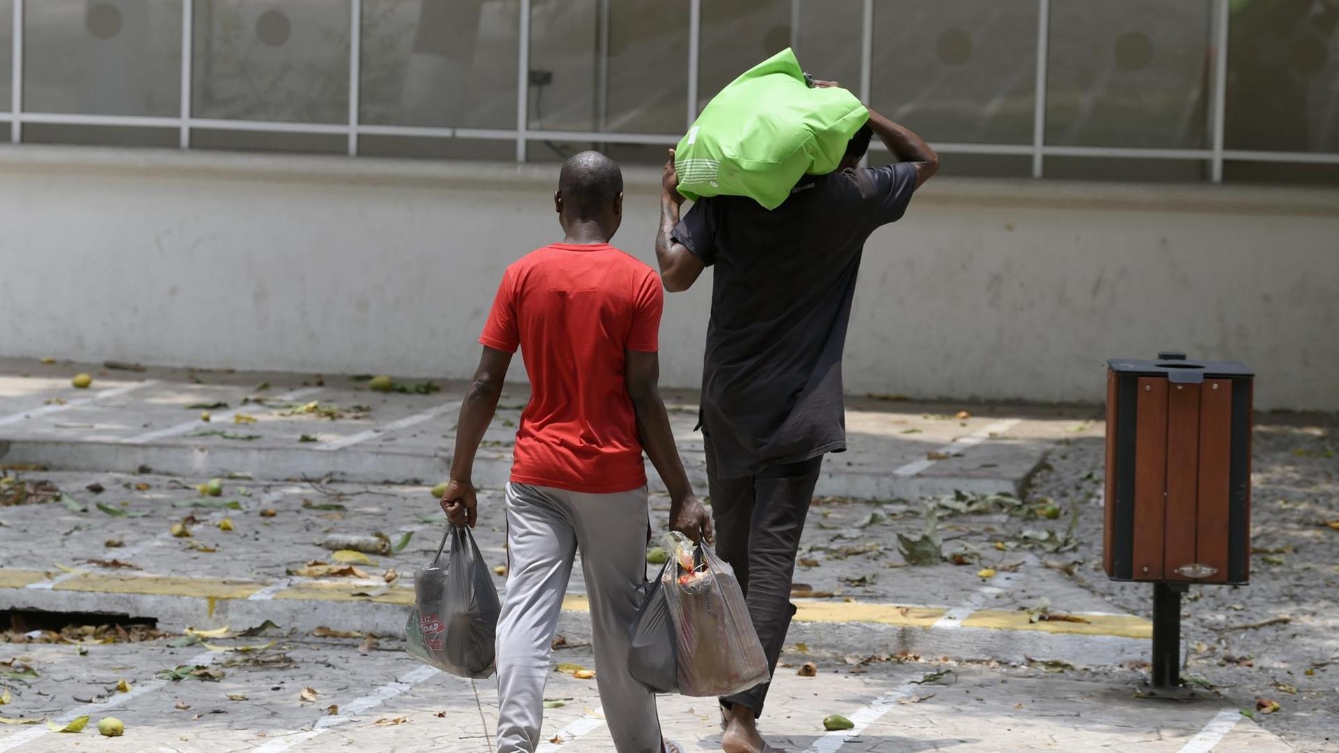 Afrikanische Flüchtlinge in Mexiko tragen ihre Taschen mit Nahrung zum 'Feria Mesoamericana'-Park in Tabachula, der als Unterkunft von Migranten aus Afrika, Indien und Haiti genutzt wird.