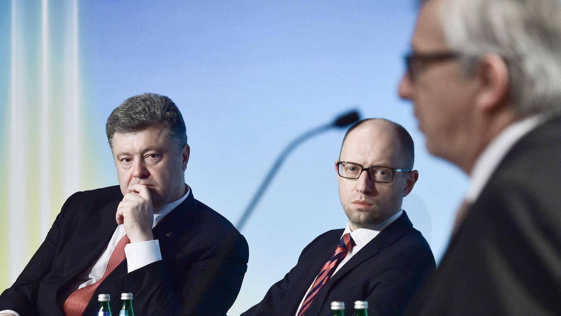 Petro Poroschenko und Arseni Jazenjuk hören Jean-Claude Juncker zu.