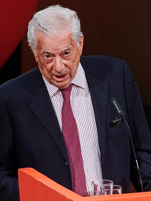 Mario Vargas Llosa hält die Festrede zur Eröffnung des Internationalen Literaturfestivals Berlin. Er steht an einem Rednerpult und wendet sich an die Zuhörerschaft.