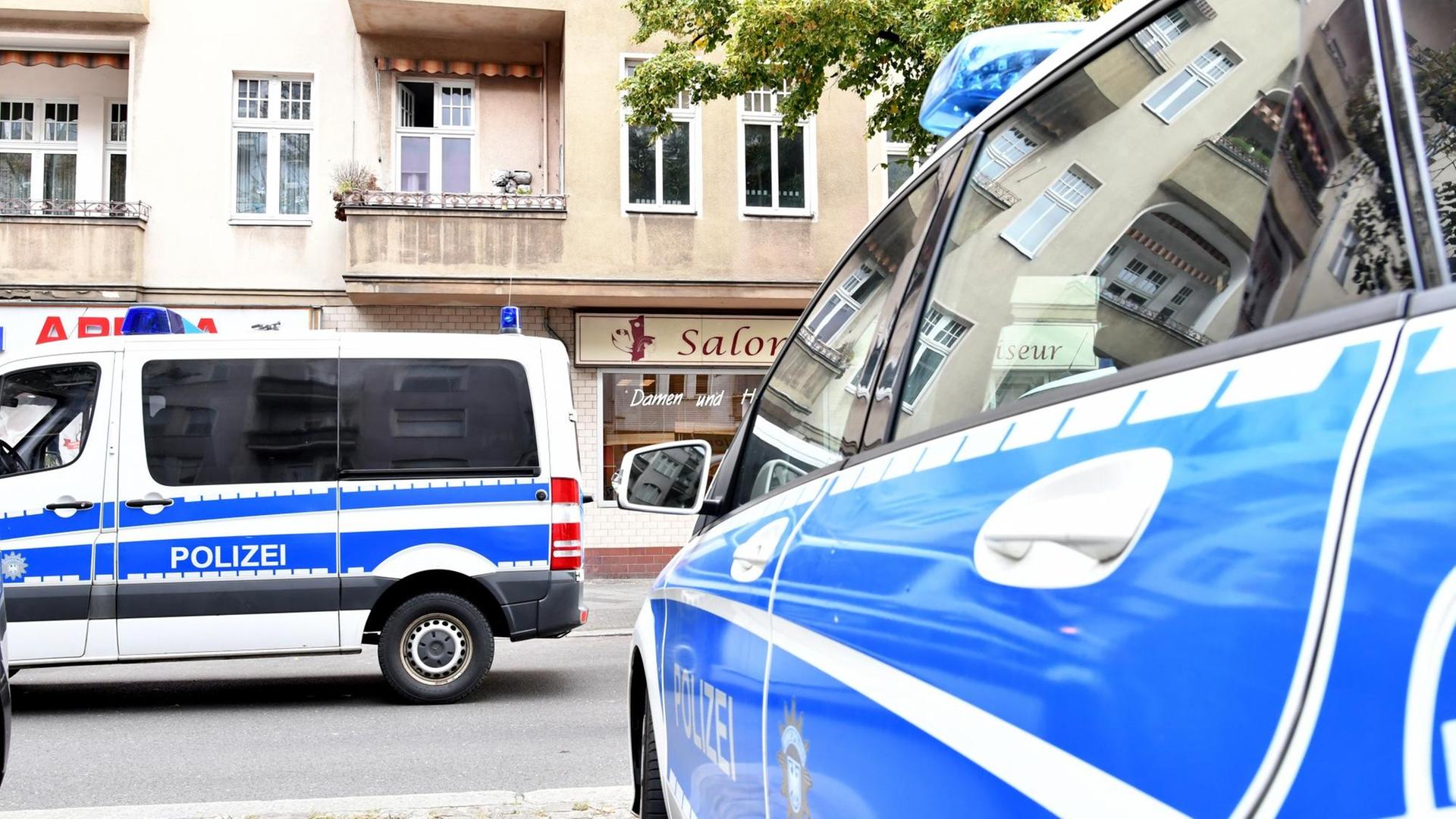 Polizeiwagen stehen während einer Razzia vor einem Haus in Berlin.