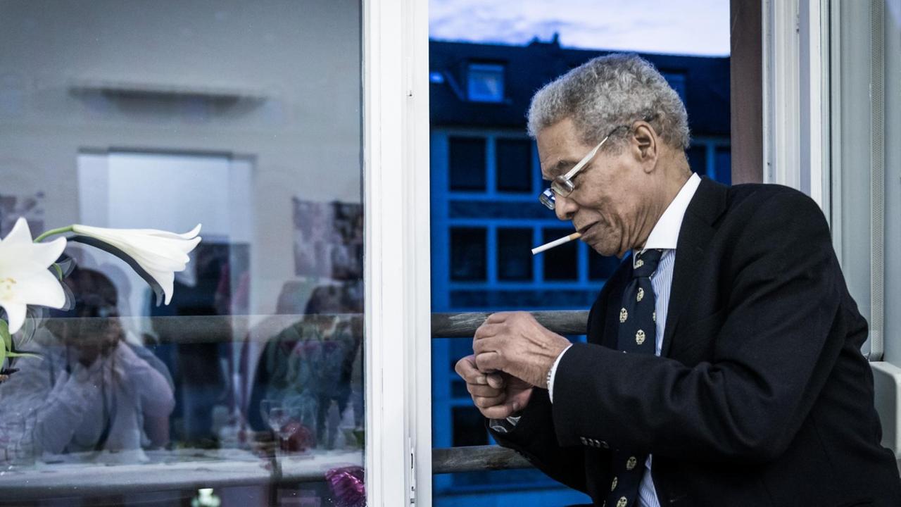 Benjamin Patterson sitzt auf einer Fensterbank und zündet sich eine Zigarette an.