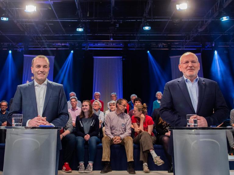 Das Bild zeigt Manfred Weber und Frans Timmermans, Sie stehen während einer Fernsehdebatte hinter Pulten.