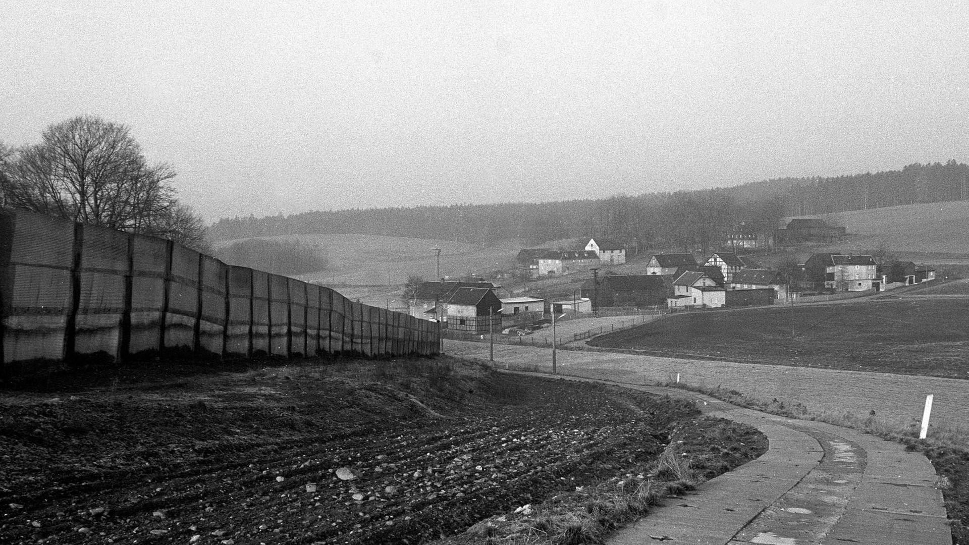 Schwarzaufnahme eines bayerischen Dorfes mit wenigen Häusern, unweit einer innerdeutschen Grenzanlage.
