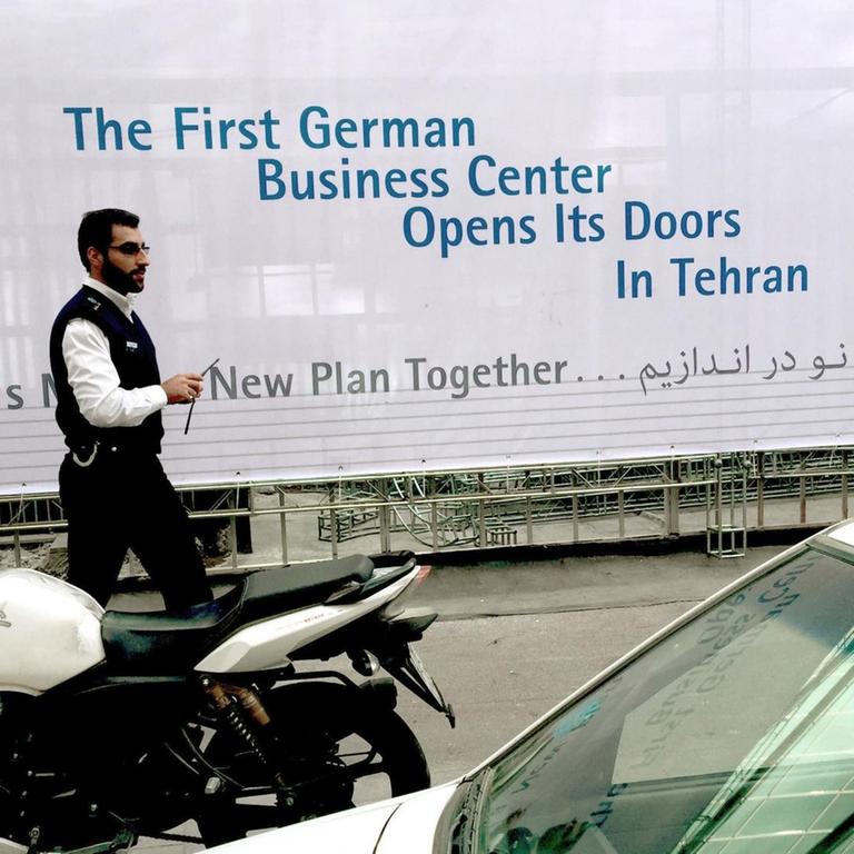 Ein Mann geht am 02.11.2017 in Teheran im Iran an einem Banner mit der Aufschrift "First German Business Center Opens its Doors in Tehran" vorbei. 