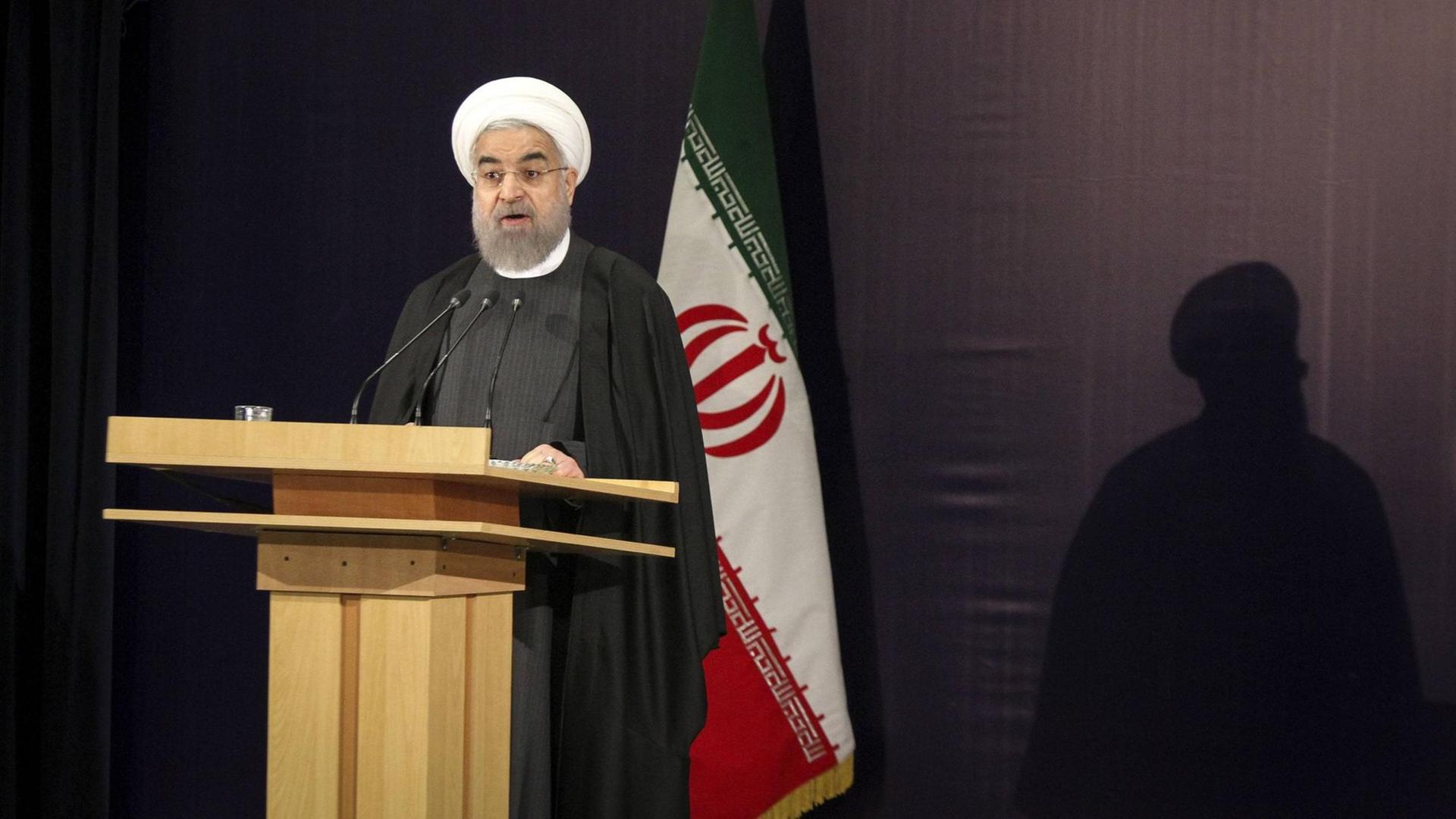 Irans Präsident Hassan Ruhani steht an einem Rednerpult und spricht.