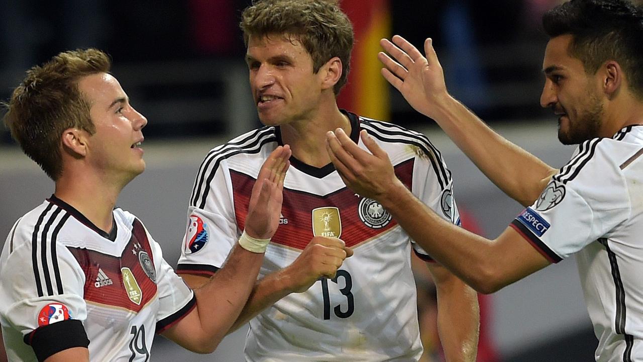Götze und Gündogan klatschen sich mit den Händen ab; Müller ruft Götze etwas zu.