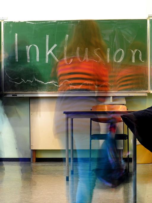 Kinder in einer Schulklasse, auf der Tafel ist das Wort Inklusion geschrieben