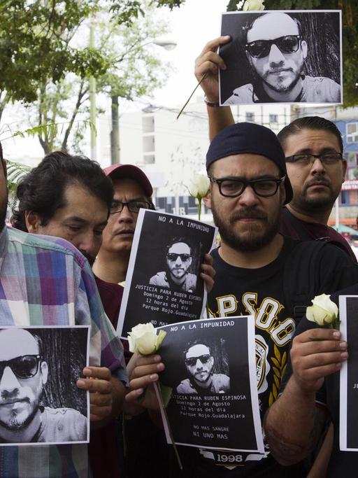 Mexikanische Journalisten halten Bilder ihres ermordeten Kollegen und weiße Blume als Zeichen der Trauer in den Händen.