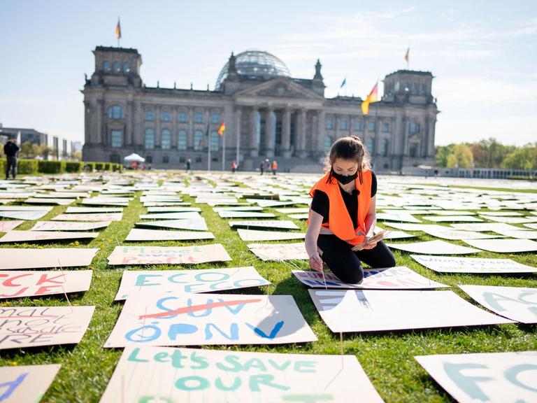 "Fridays for Future"-Protest in Corona-Zeiten: Die Aktivistin Luisa Neubauer legt auf der Wiese vor dem Bundestag Protestplakate aus. Sie sitzt auf der Wiese inmitten hunderter Plakate, im Hintergrund der Reichstag.