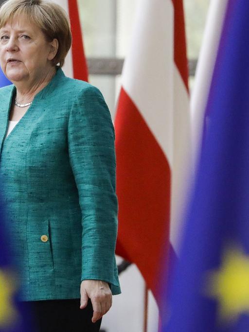Bundeskanzlerin Angela Merkel läuft zwischen EU-Fahnen auf einem EU-Gipfel am 28. Juni 2018.