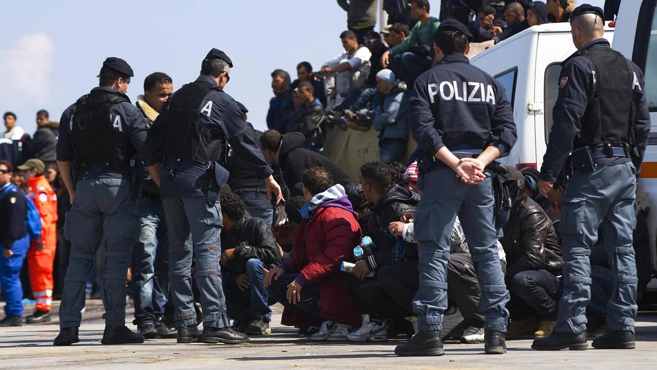 Am Hafen von Lampedusa stehen 2011 Flüchtlinge und Polizisten Am Hafen von Lampedusa stehen 2011 Flüchtlinge und Polizisten