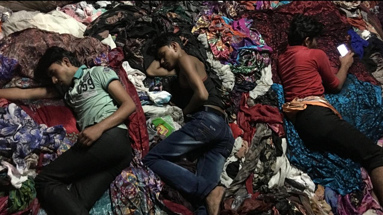 Filmstill aus dem Film "Machines" von Rahul Jain. Arbeiter schlafen vor Erschöpfung während der Arbeitszeit in einer indischen Textilfabrik.