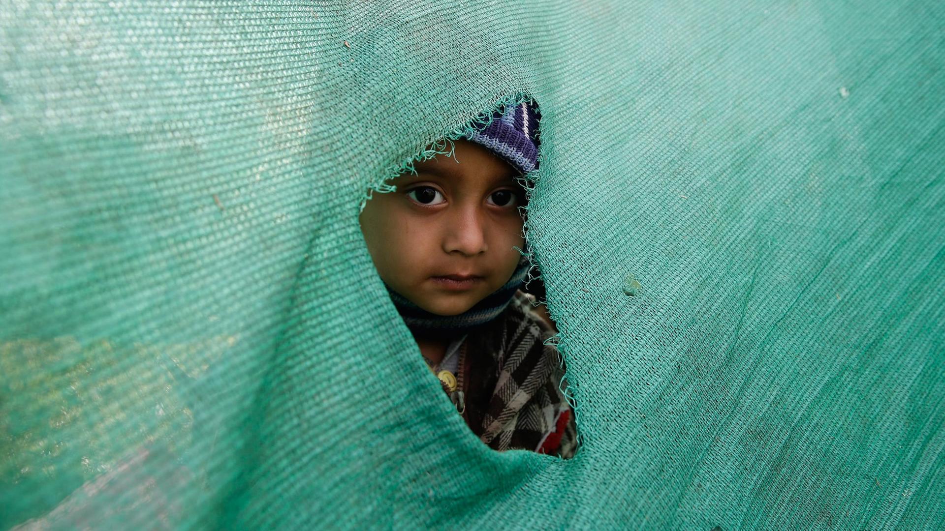 In Kathmandu schaut ein Kind durch ein Loch in einer Zeltwand nach draußen. A child peeks out of a hole in a temporary tent in an open ground in Kathmandu after a powerful earthquake followed by strong aftershocks struck Nepal, in Kathmandu, Nepal, 27 April 2015.