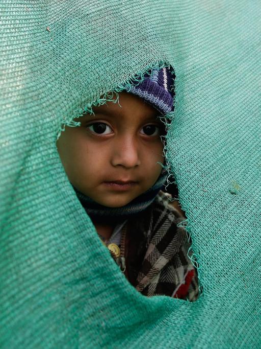 In Kathmandu schaut ein Kind durch ein Loch in einer Zeltwand nach draußen. A child peeks out of a hole in a temporary tent in an open ground in Kathmandu after a powerful earthquake followed by strong aftershocks struck Nepal, in Kathmandu, Nepal, 27 April 2015.