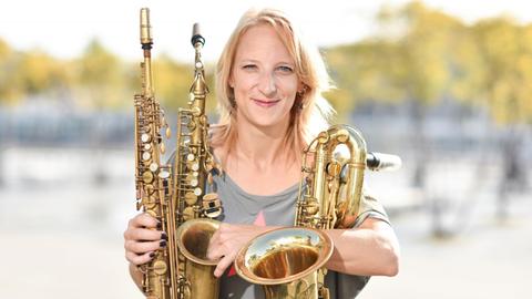 Die Saxophonistin Alexandra Lehmler sitzt am 17.09.2014 in Mannheim (Baden-Württemberg) mit verschiedenen Saxophonen auf einer Bank.