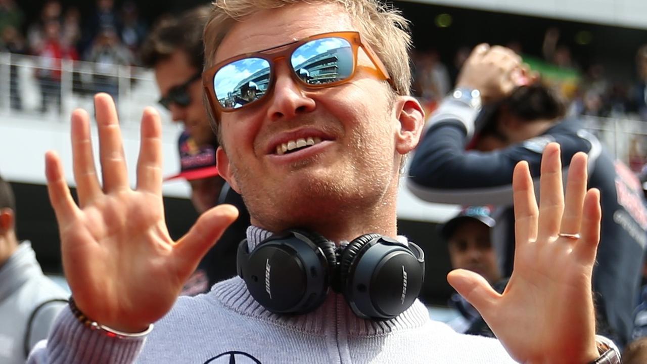 Nico Rosberg lächelt mit verspiegelter Sonnenbrille in die Kamera und hebt beide Hände.
