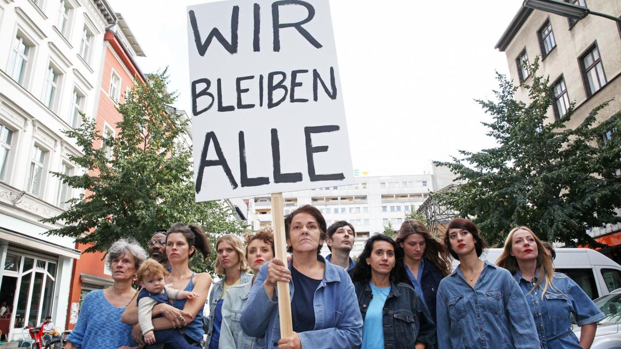 Protestierende Frauen tragen ein Plakat mit der Aufschrift "Wir bleiben alle"

