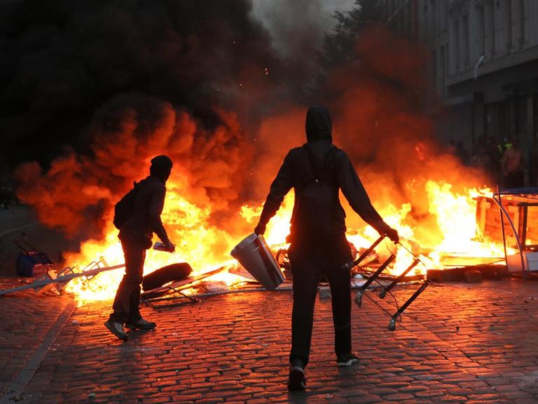 Randalierer stehen im Schanzenviertel in Hamburg vor einer brennenden Barrikade.